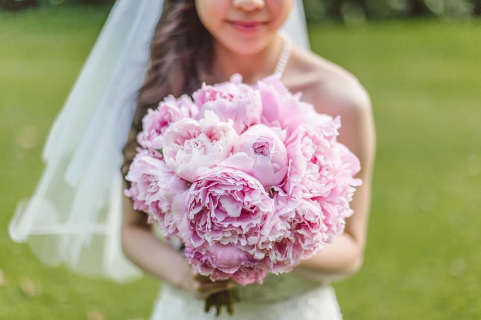Free Image of Bride holding a lush pink peony bouquet 
