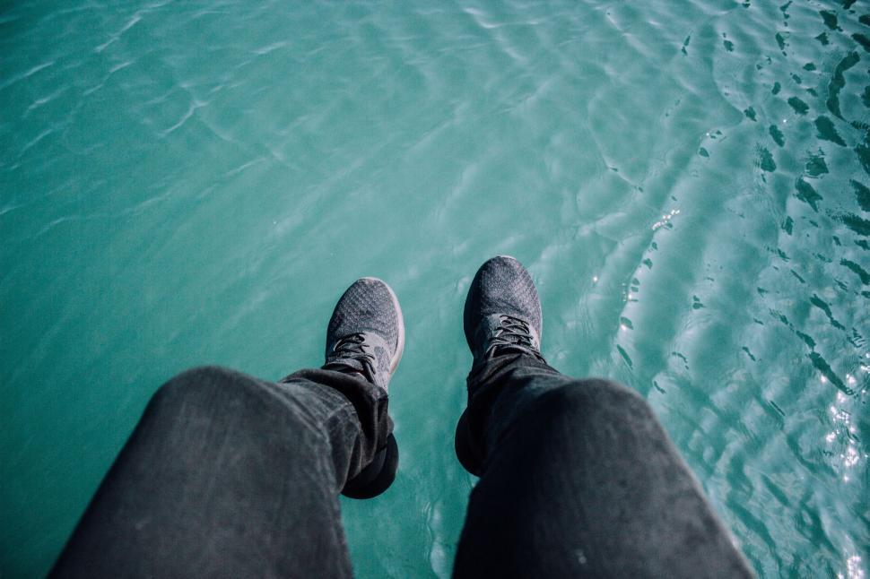 Free Image of Feet dangling over clear turquoise water 