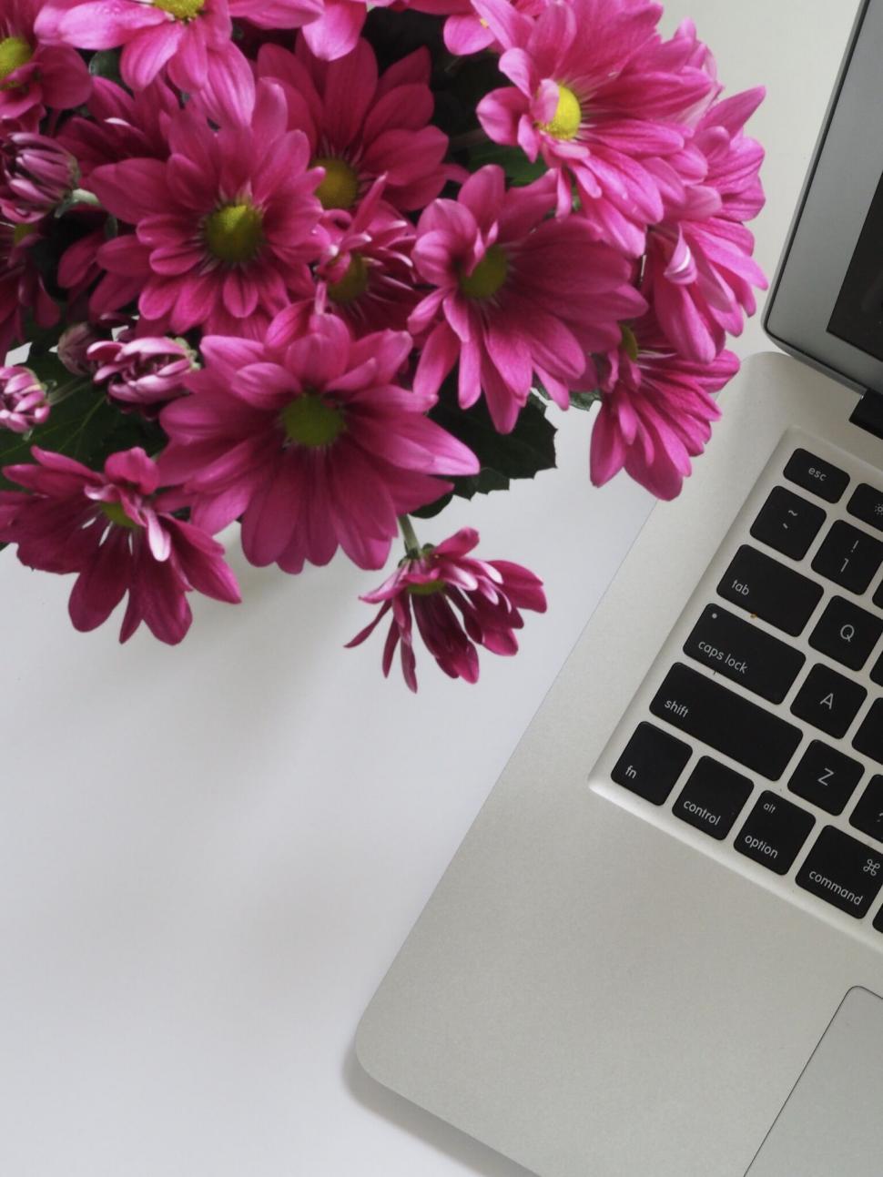 Free Image of Laptop with pink flowers arrangement on desk 