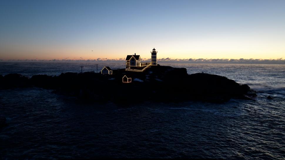 Free Image of Lighthouse silhouetted against sunset sky 