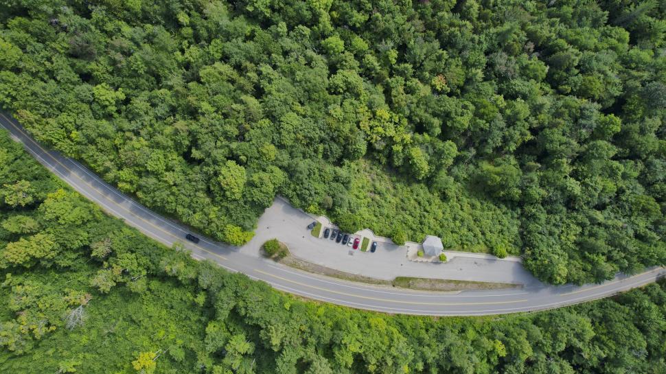 Free Image of Aerial view of parking area surrounded by dense forest. 