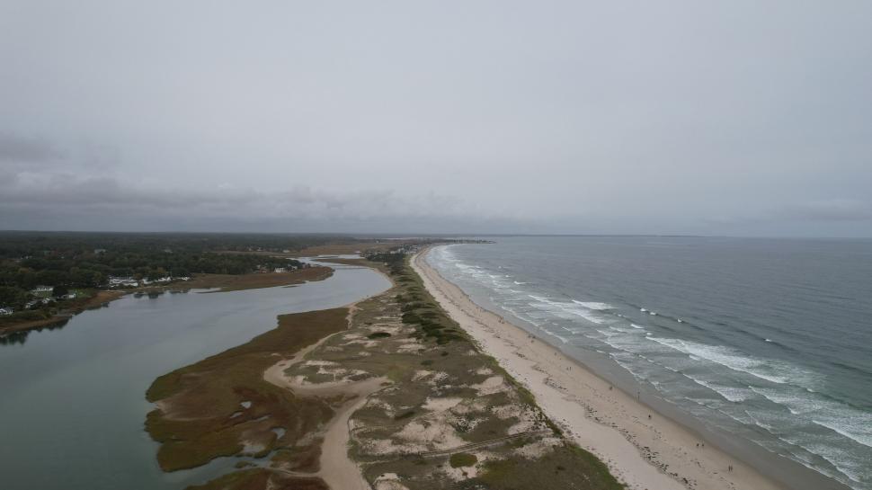 Free Image of Aerial view of a long sandy beach meets the ocean. 