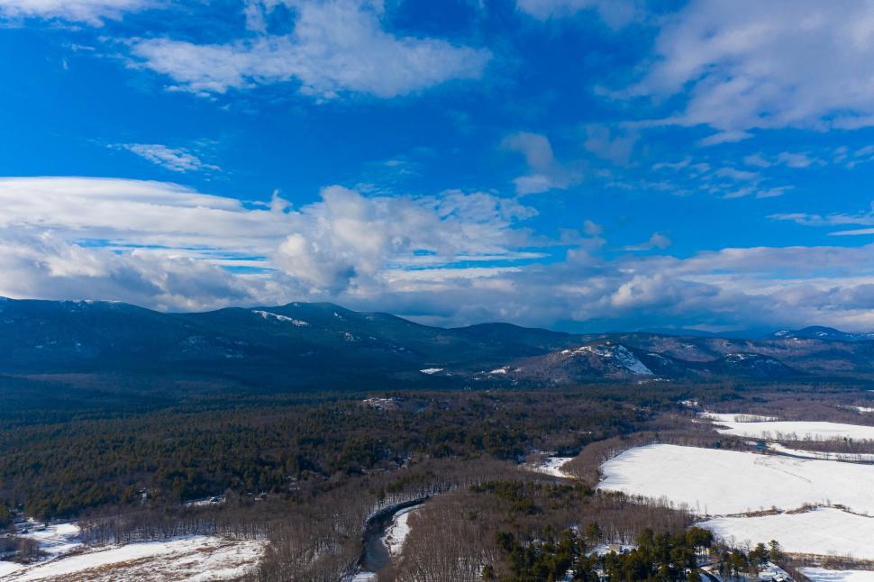 Free Image of Snowy valley with river and distant mountains in background. 