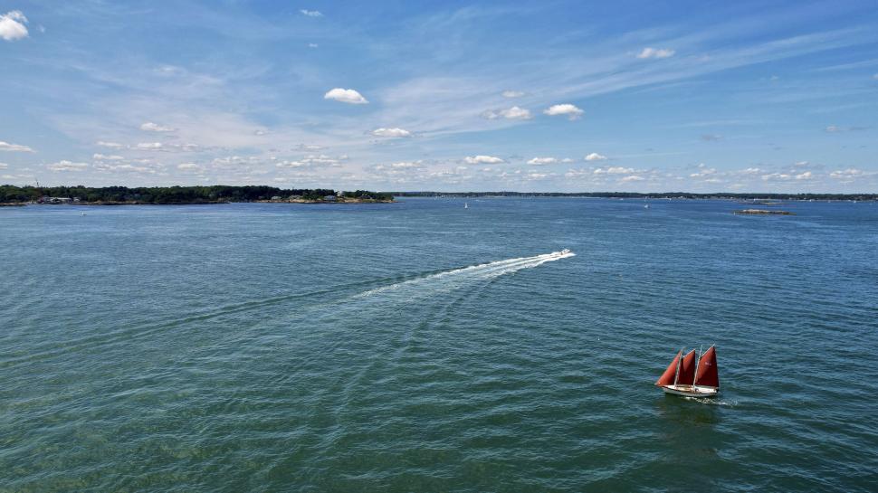 Free Image of Sailboat with red sails on a calm blue ocean expanse 