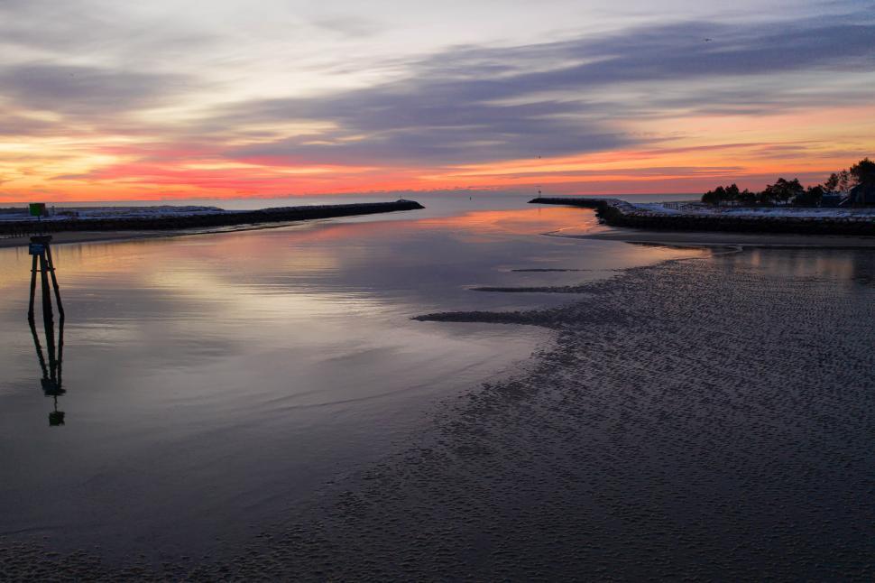 Free Image of Calm inlet opening to ocean during a vibrant, colorful sunset 