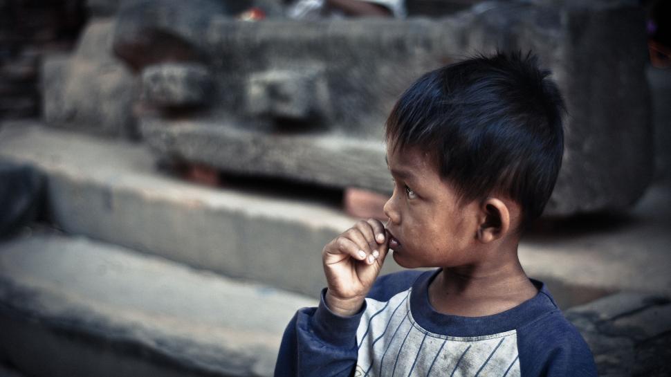 Free Image of Young boy deep in thought with hand near his mouth 