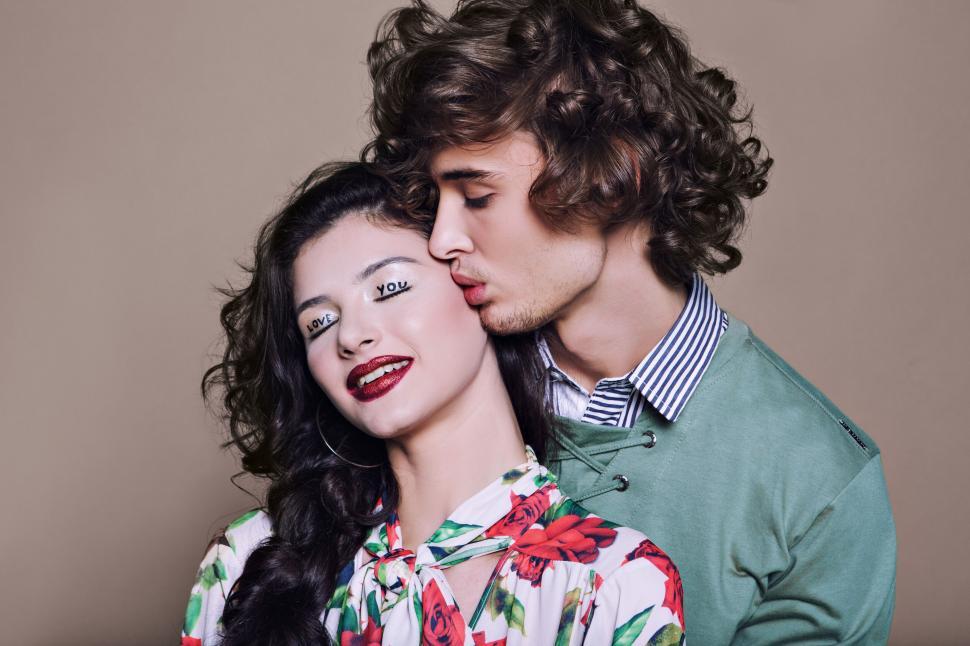 Free Image of Man kisses woman on cheek while she smiles at camera 