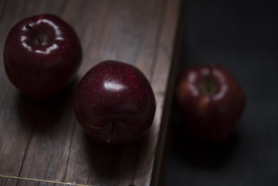 Free Image of Three shiny red apples on dark wooden table surface 