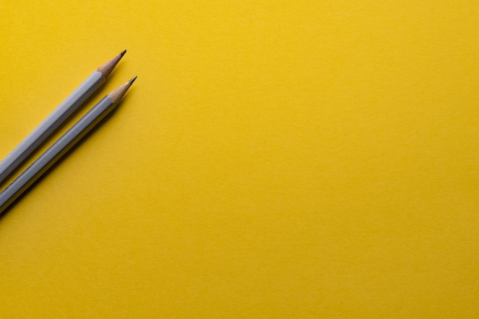 Free Image of Two pencils on vibrant yellow background abstract scene 