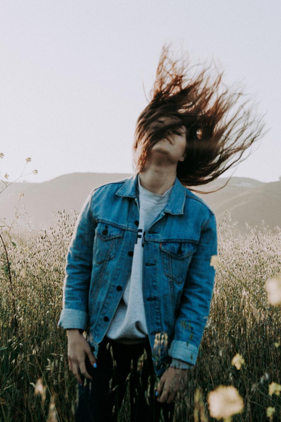 Free Image of Person flipping hair in a field bathed in sunset light. 