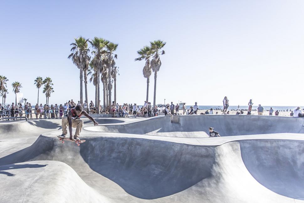 Free Image of Skateboarder mid-air trick at a busy outdoor skatepark. 