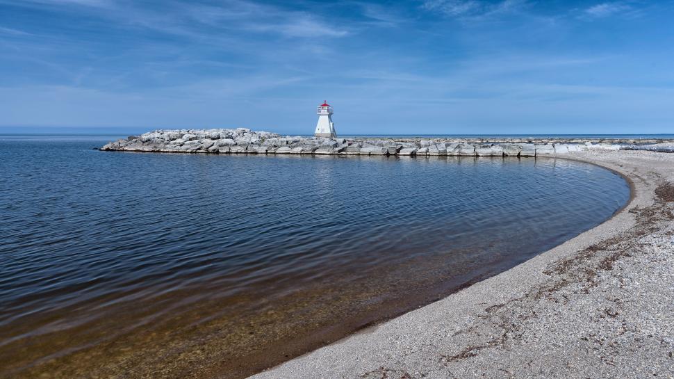 Free Image of Coastal landscape with a lighthouse and rocky shoreline. 