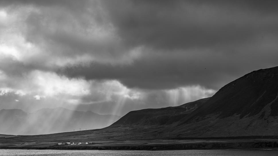 Free Image of Rays of sunlight piercing through cloudy sky over mountain 