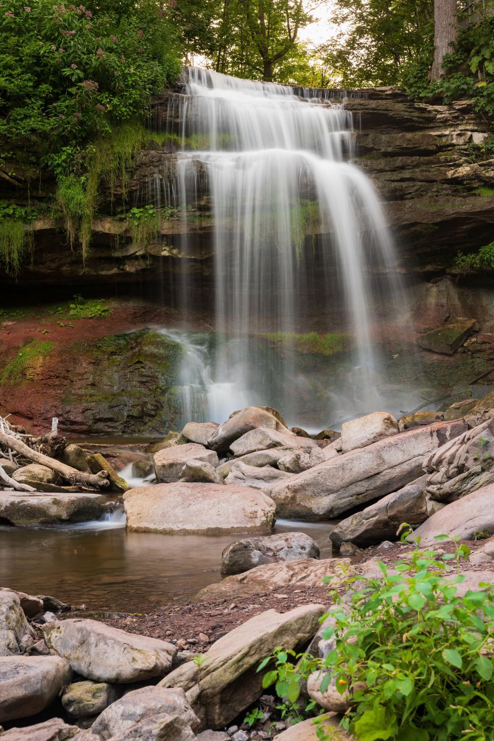 Free Image of Waterfall cascading over rocks in a lush forest area. 
