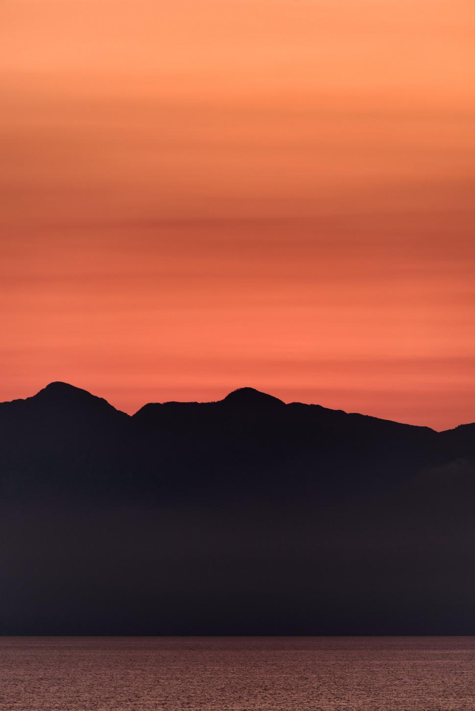 Free Image of Silhouetted mountains against an orange sunset sky. 