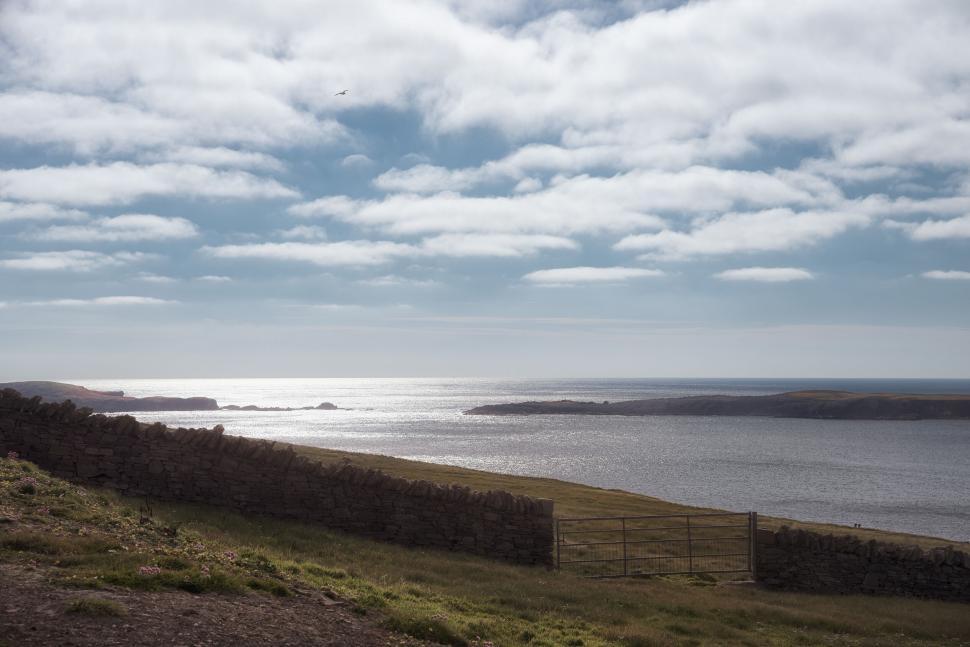 Free Image of Scenic coastal view with cloudy sky and calm waters. 