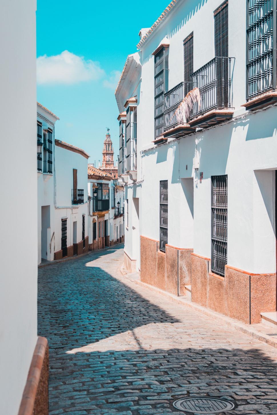 Free Image of Narrow street in charming town with church in distance. 