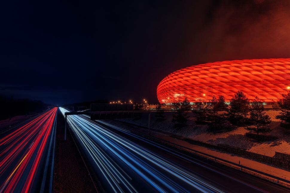 Free Image of Dramatic light trails on highway near iconic stadium 