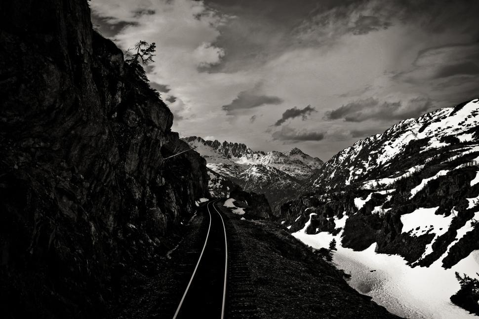 Free Image of Railroad tracks through a dramatic mountain landscape. 