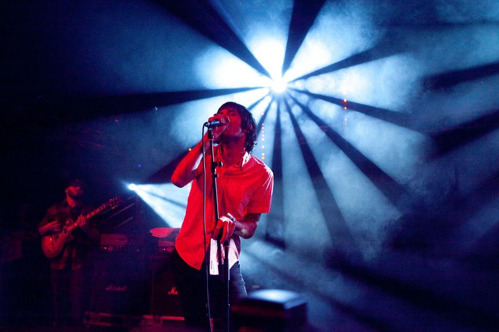 Free Image of Singer performing on stage under dramatic blue lighting. 