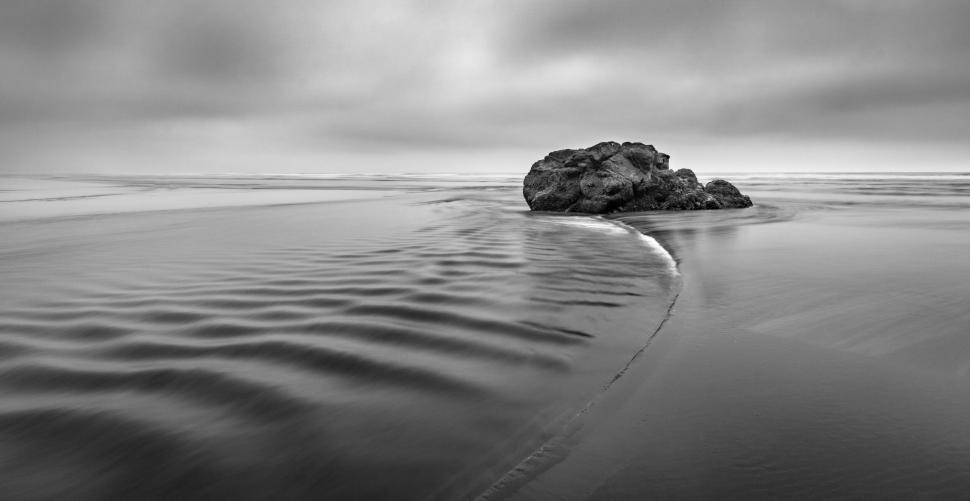 Free Image of Serene coastline with rock and smooth water flow. 