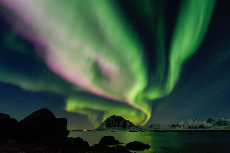 Free Image of Aurora Borealis over snowy mountain and dark waters. 
