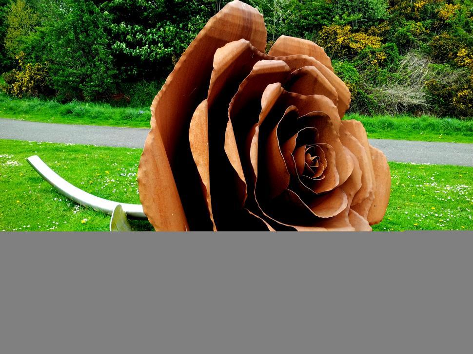 Free Image of Gigantic metal rose sculpture on lush green grass lawn. 