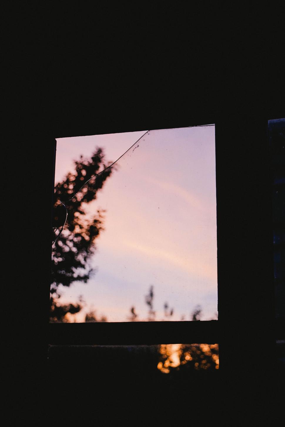 Free Image of Dusky sky seen through a window with tree silhouette. 