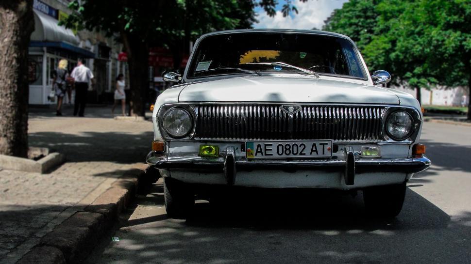 Free Image of Retro white car parked on a busy urban street scene 