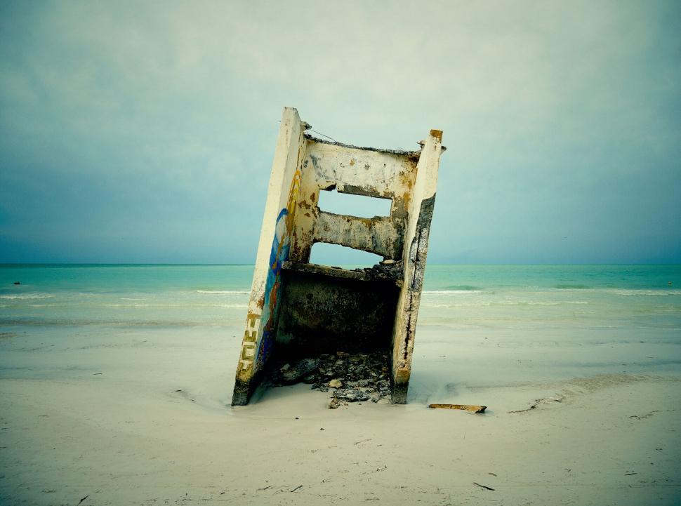 Free Image of Weathered concrete structure leans on an empty beach shore 