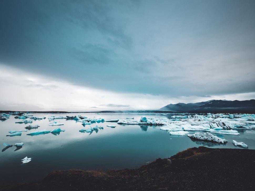 Free Image of Icy landscape with floating icebergs under cloudy sky. 