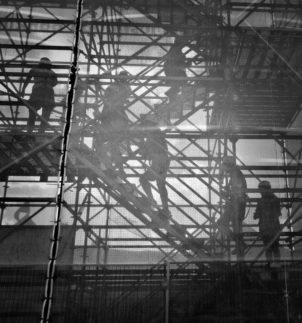 Free Image of Silhouettes of people on staircase through netted structure. 