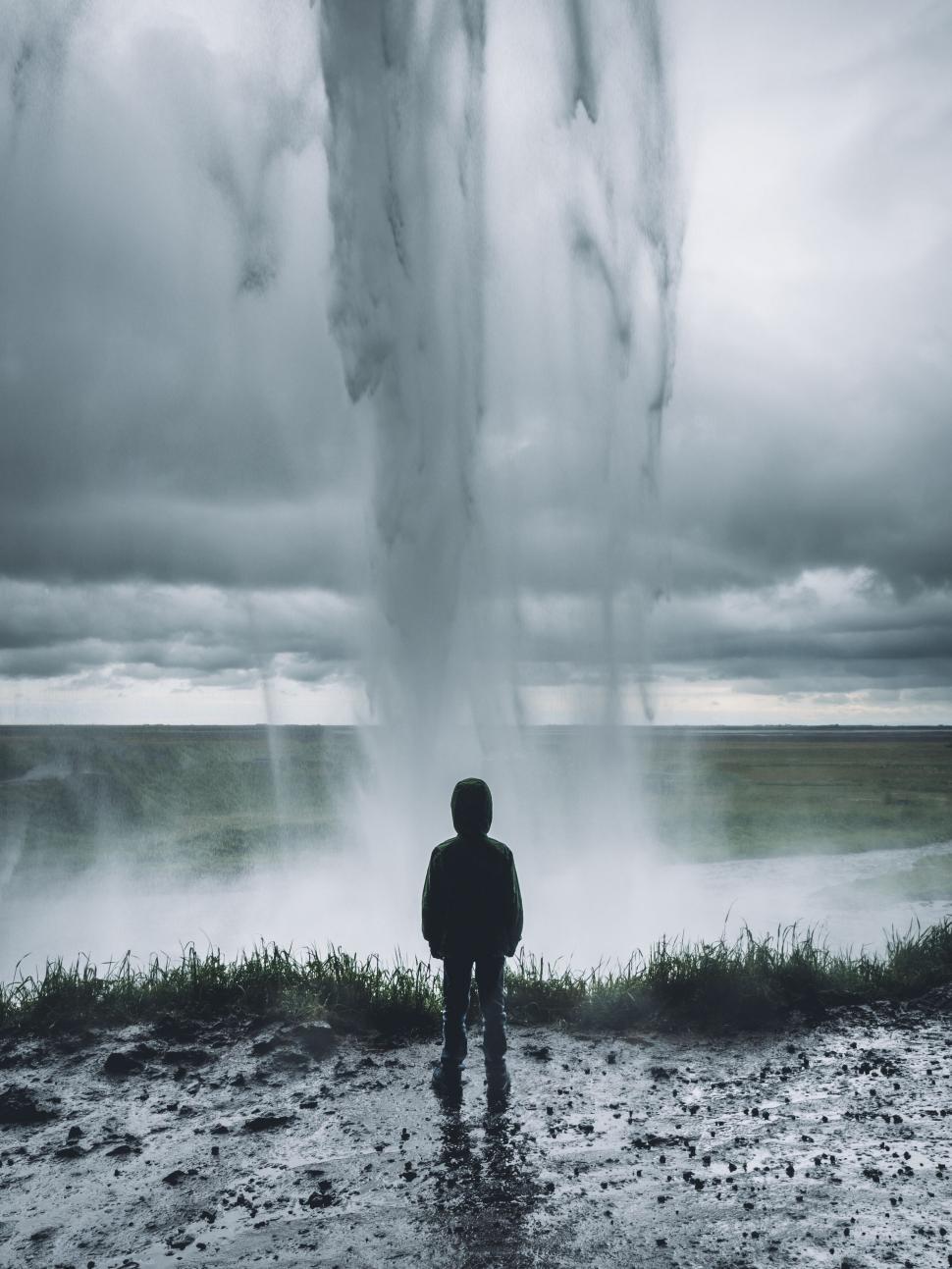 Free Image of Silhouette of person standing behind a large waterfall. 
