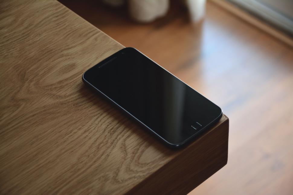 Free Image of Single black smartphone resting on wooden surface 
