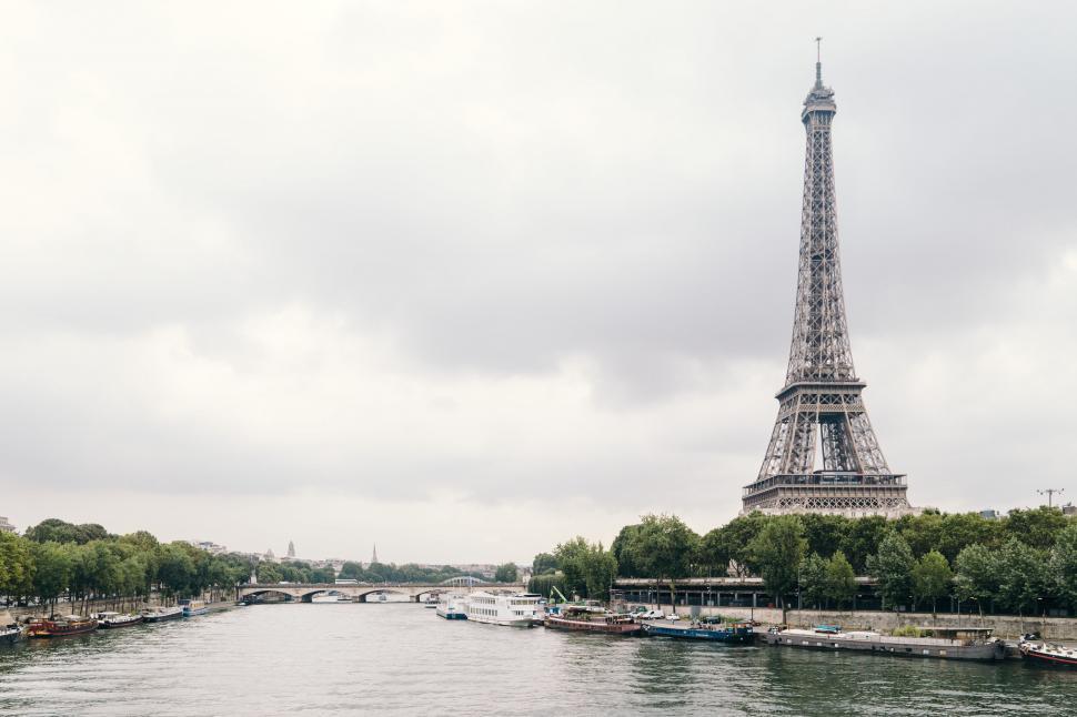 Free Image of Eiffel Tower by the river under cloudy skies 