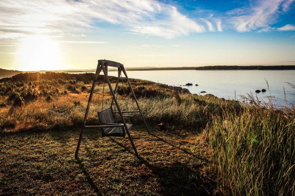 Free Image of Swing bench facing a tranquil lakeshore at sunset hour. 