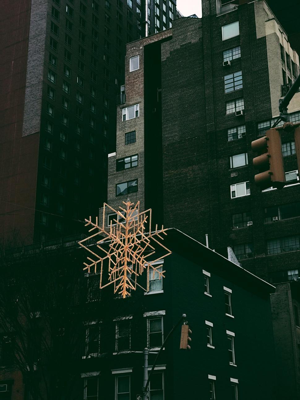 Free Image of Snowflake decoration on urban high-rise building background 