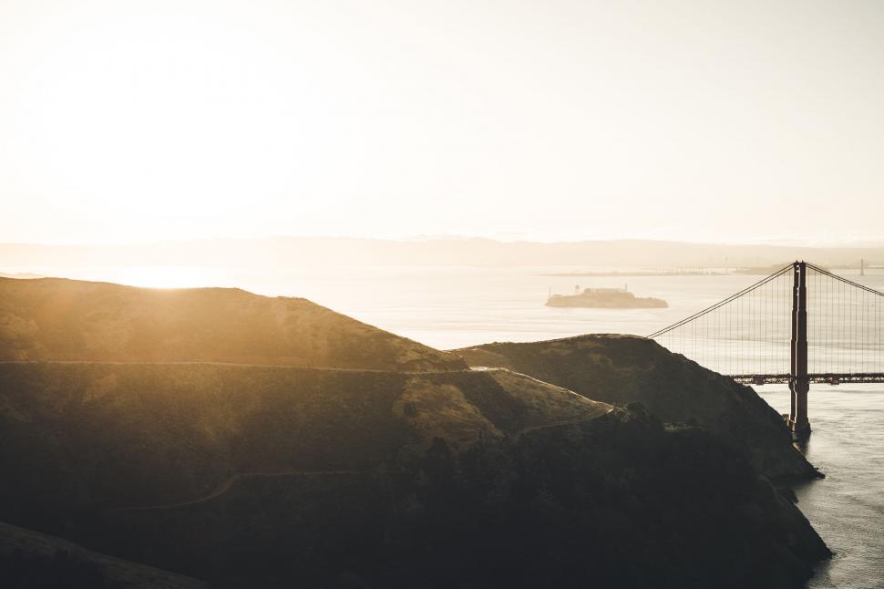 Free Image of Sunset over hillside with bridge and distant island 
