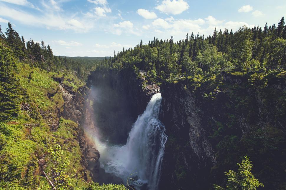 Free Image of Majestic waterfall amid lush green forest landscape. 