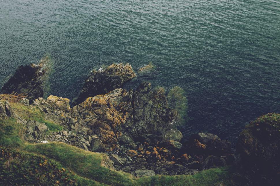 Free Image of Rocky coastline meeting blue ocean waves, tranquil view. 