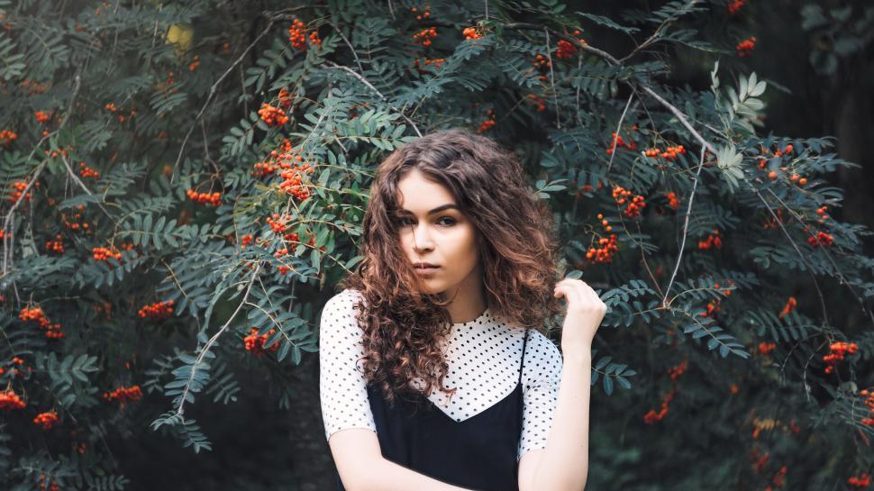 Free Image of Person wearing polka dot top outdoors among trees 