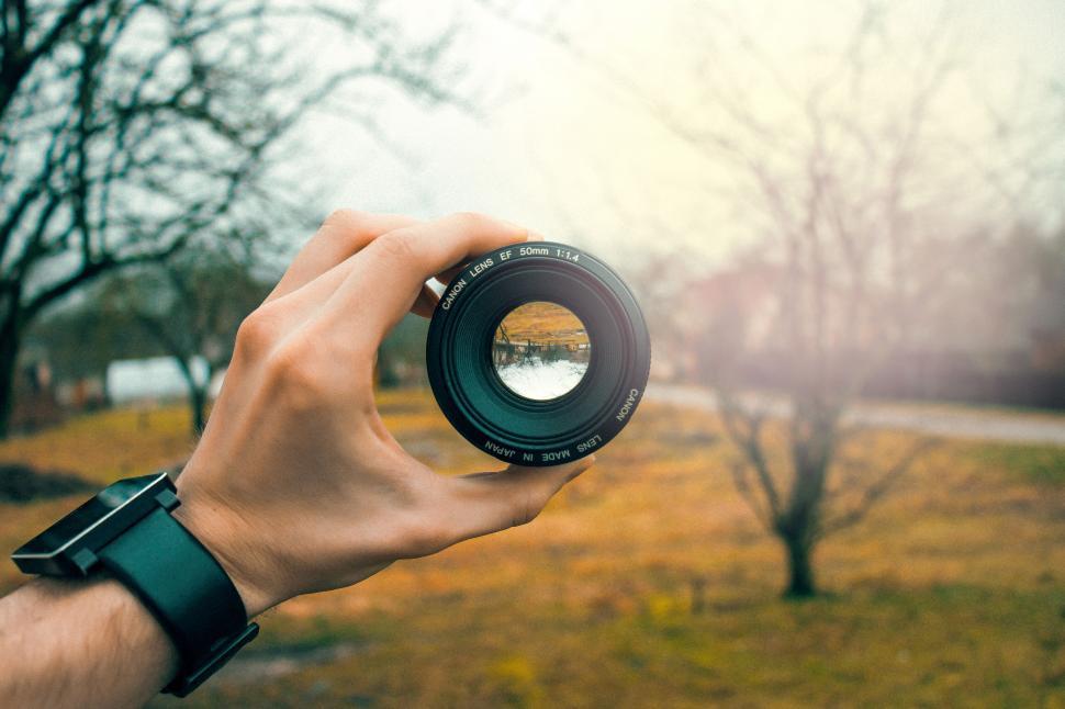 Free Image of Hand holding a camera lens with outdoor scenery view 