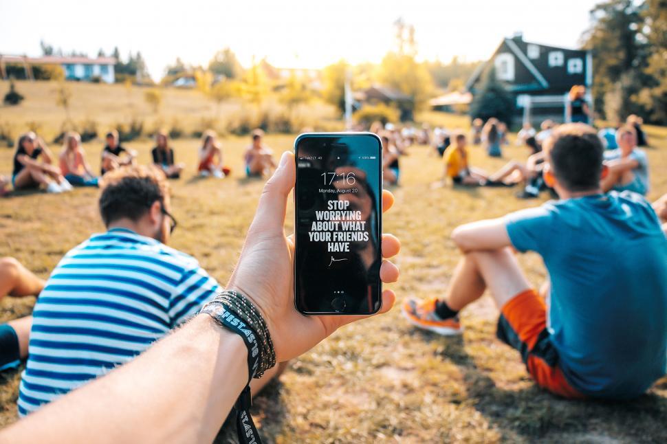 Free Image of Person holding phone with quote at outdoor gathering. 