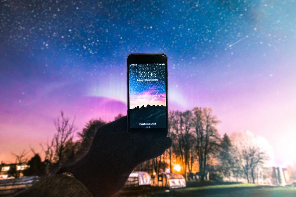 Free Image of Hand holding smartphone against scenic night sky view 