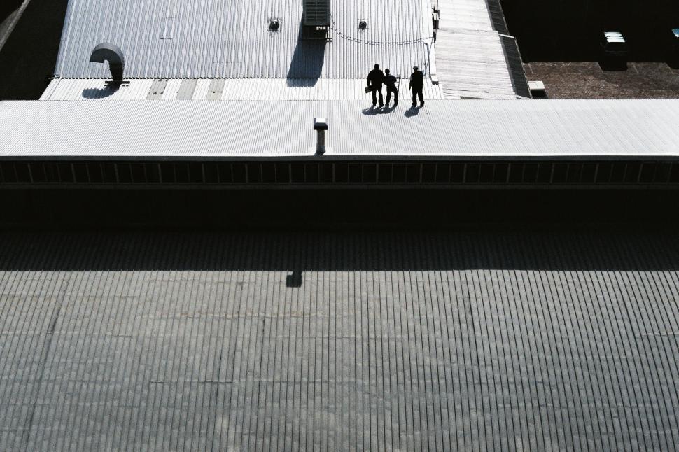 Free Image of Three silhouetted figures on industrial building rooftop 