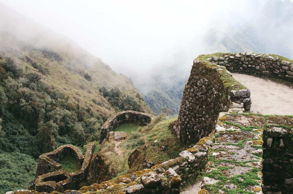 Free Image of Ancient stone ruins surrounded by misty green mountains. 