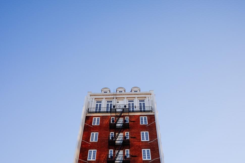 Free Image of Red-bricked multi-story building against clear blue sky. 