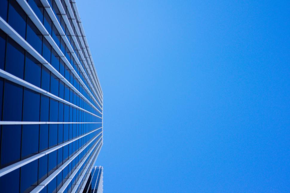 Free Image of Upward view of modern glass skyscraper with blue facade. 