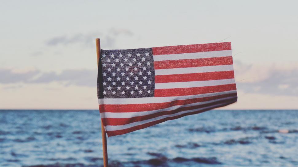 Free Image of Small American flag on a pole fluttering by the sea 
