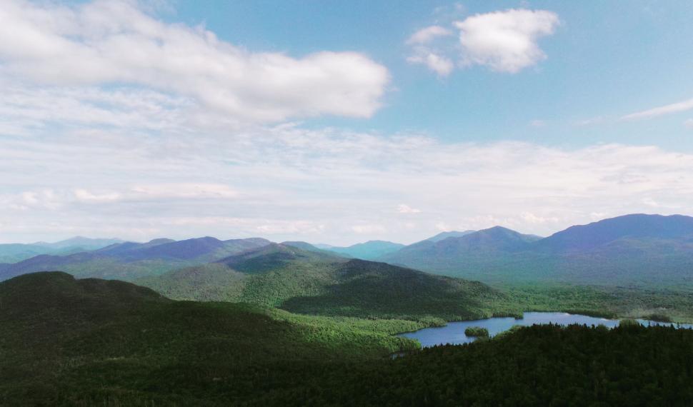 Free Image of Expansive view of green valleys and mountains under sky 